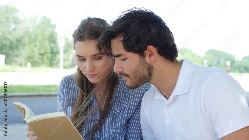 couple of young students man and woman working together with a laptop computer outdoor in a street during summer couple of young students man and woman working together with a laptop computer outdoor in a street during summer