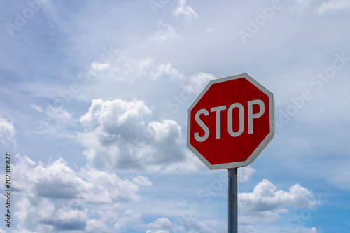Red stop sign and blue sky with white clouds in background