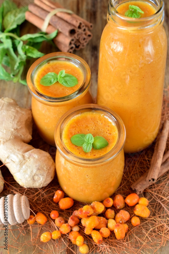 Yellow smoothie with berries of sea buckthorn in glass jars decorated with mint