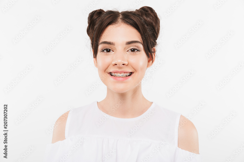 Portrait closeup of beautiful teenage girl 20s with double buns hairstyle and dental braces smiling at camera in happy mood, isolated over white background Portrait closeup of beautiful teenage girl 20s with double buns hairstyle and dental braces smiling at camera in happy mood, isolated over white background