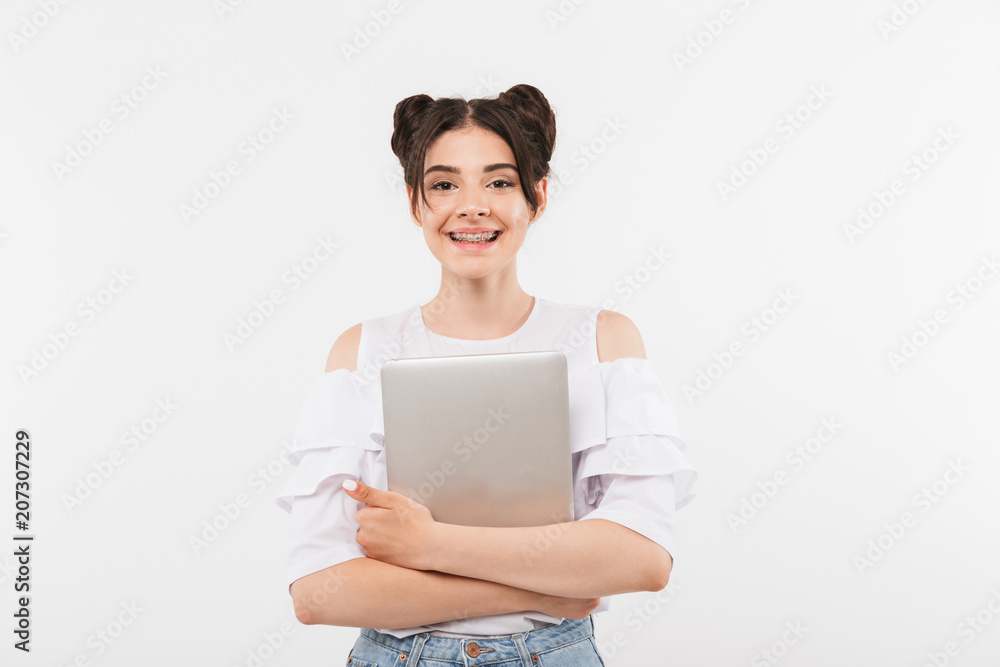 Photo of educated joyful woman with double buns hairstyle smiling and hugging silver laptop, isolated over white background Photo of educated joyful woman with double buns hairstyle smiling and hugging silver laptop, isolated over white background