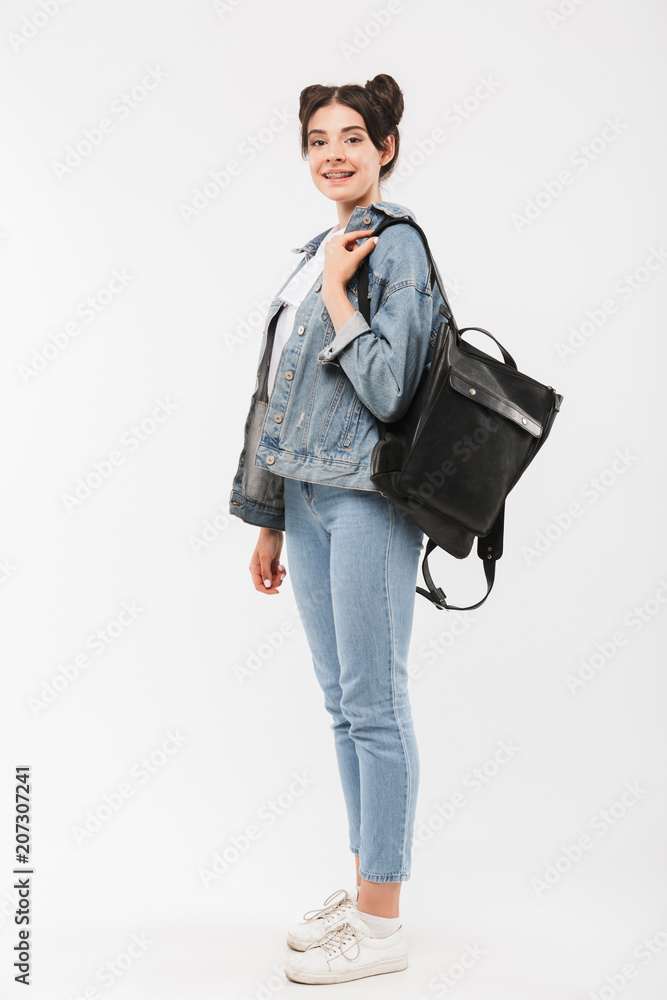 Full length photo of beautiful teenage girl 20s with double buns hairstyle wearing jeans clothing and backpack smiling at camera, isolated over white background Full length photo of beautiful teenage girl 20s with double buns hairstyle wearing jeans clothing and backpack smiling at camera, isolated over white background