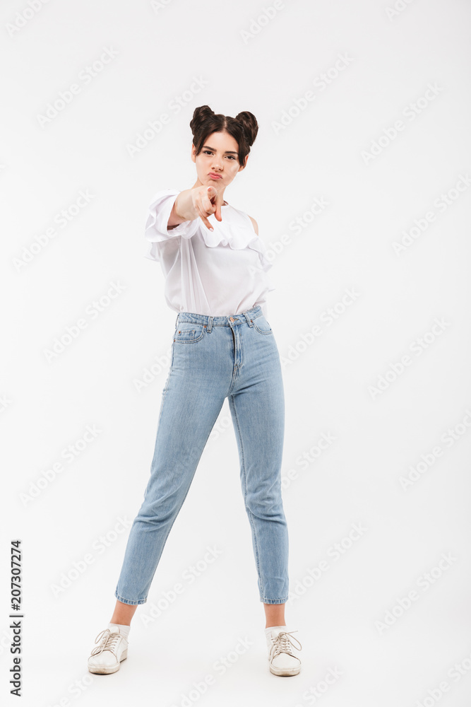 Full length portrait of serious strict girl having double buns hairstyle pointing finger at camera with blame, isolated over white background in studio Full length portrait of serious strict girl having double buns hairstyle pointing finger at camera with blame, isolated over white background in studio