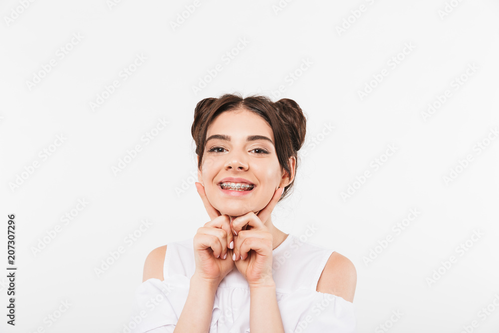 Portrait closeup of joyful smiling girl 20s with double buns hairstyle laughing and showing dental braces, isolated over white background Portrait closeup of joyful smiling girl 20s with double buns hairstyle laughing and showing dental braces, isolated over white background