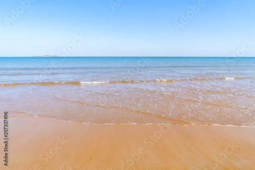 The sea and sand under a clear sky photo