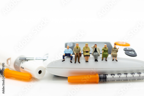 Miniature people sitting on glucose meter with lancet. Image use for medicine  diabetes  health care concept.