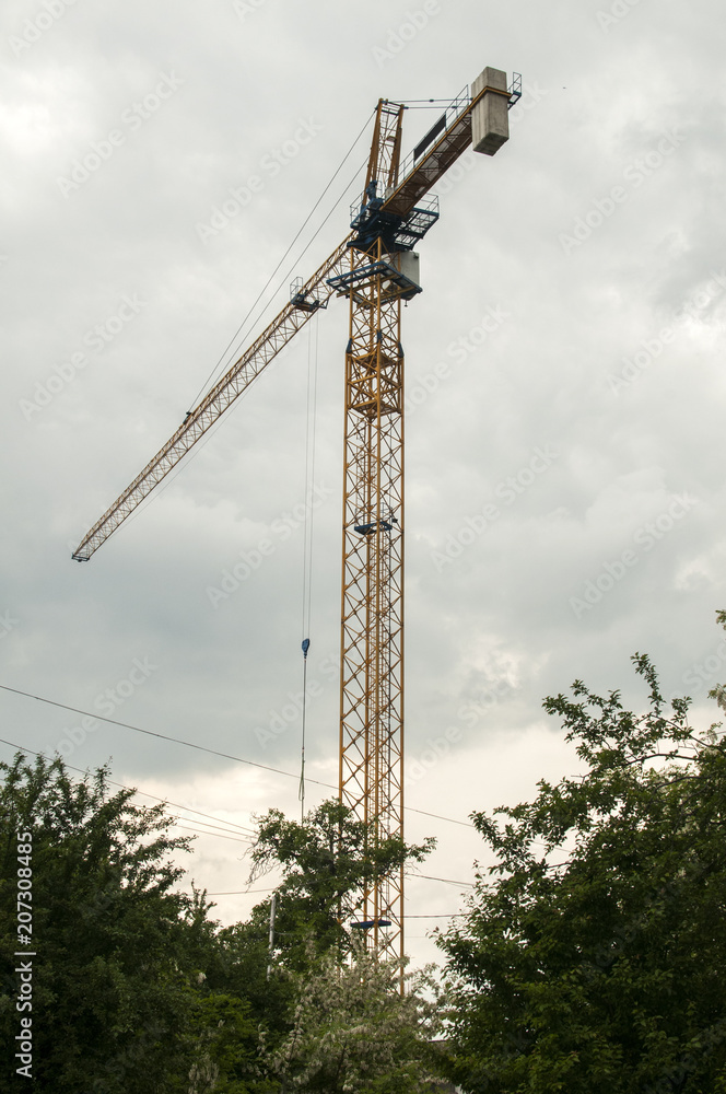 Construction tower crane in action against the cloudy sky Construction tower crane in action against the cloudy sky