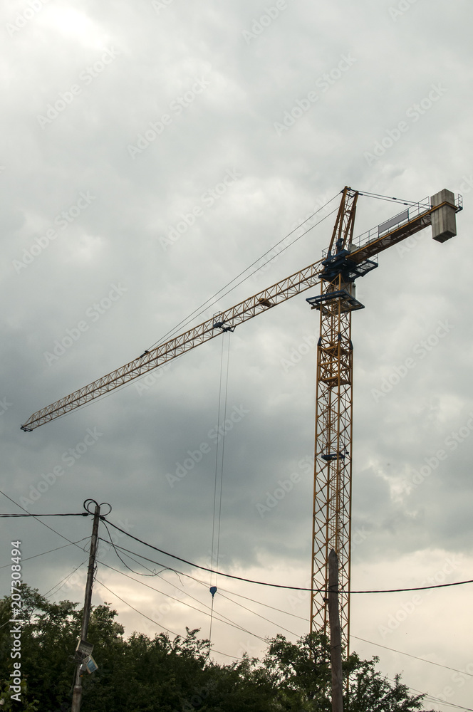 Construction tower crane in action against the cloudy sky