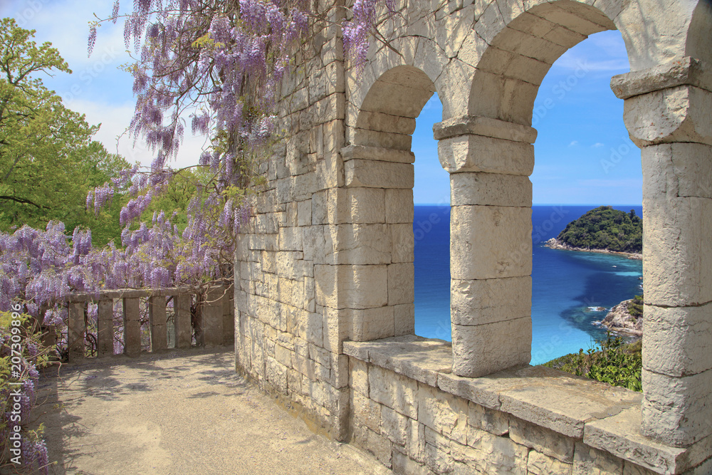 Beautiful view of the loggia and on the sea, a loggia of natural stone the masonry with arched windows ,  blossoming Wisteria on the loggia