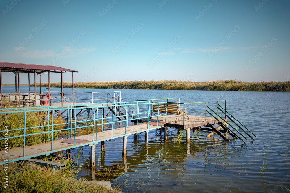 A place for fishing on the river. Wooden bridge on the river. Arbor for rest by the water