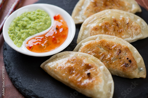Close-up of roasted korean potstickers served with dipping sauces, horizontal shot, selective focus