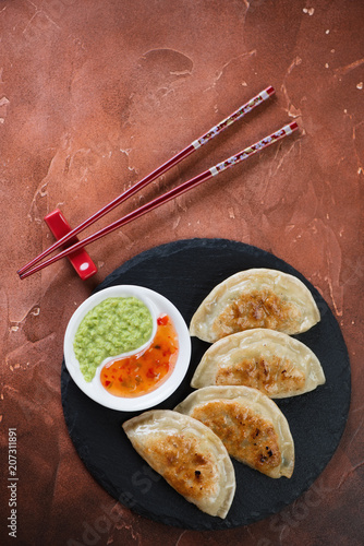 Stone slate tray with roasted potstickers, flat-lay on a fire warm rusty metal background, vertical shot with space