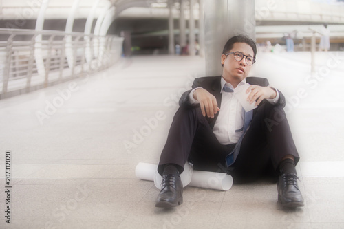 Stressful businessman or engineer sitting outdoor thoughtful thinking with hopeless