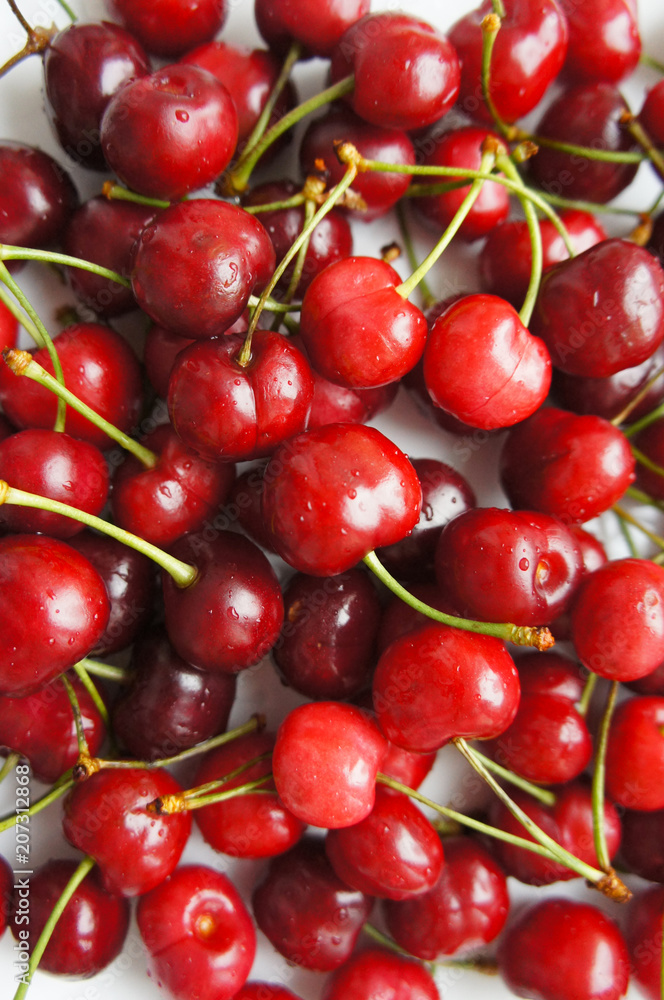 Raw red sweet cherry berries on white plate Raw red sweet cherry berries on white plate