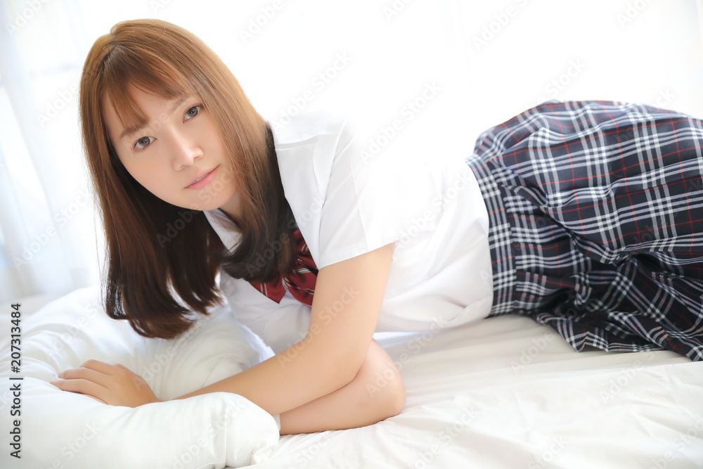Portrait japanese school girl costume sleeping and smile in white tone bed room Portrait japanese school girl costume sleeping and smile in white tone bed room