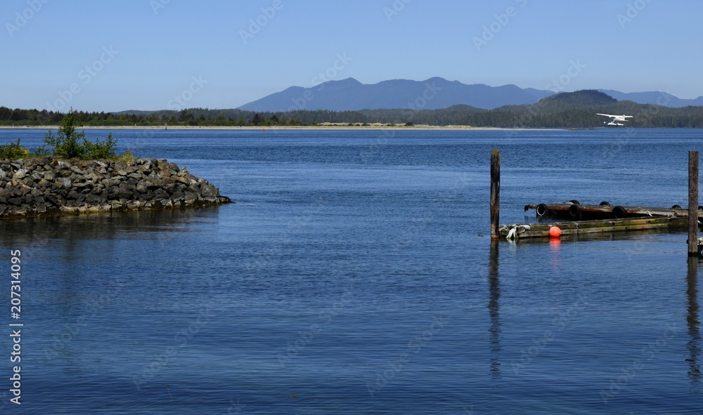 View across the bay towards islands and Mountains, float plane landing in the bay, seen from Tofino, Vancouver Island British Columbia Canada