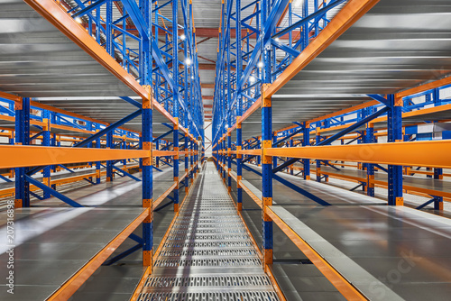 Empty shelves in new distribution warehouse. Metal equipment for storage, racks blue orange, pallet racking system photo