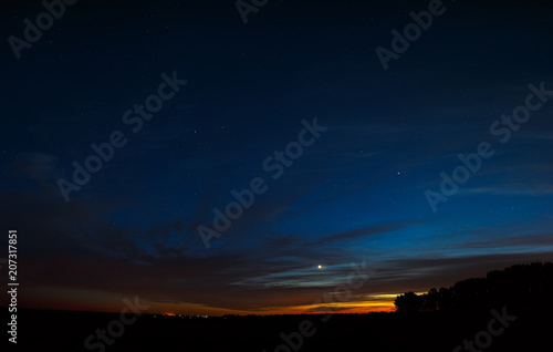 Venus in the night sky with stars. A bright sunset with clouds. Cosmic space above the earth's surface. Long exposure.