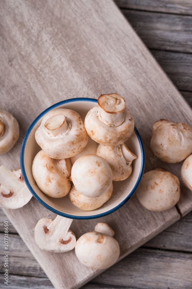 Fresh champignons on a cutting board and in a bowl 