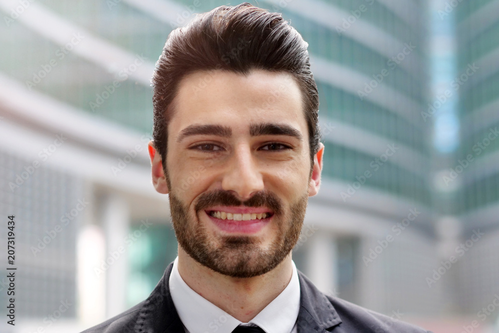 Portrait of a business man, in a suit and tie, happy and smiling as he looks at the camera and in the background buildings. Concept of: success and finance Portrait of a business man, in a suit and tie, happy and smiling as he looks at the camera and in the background buildings. Concept of: success and finance
