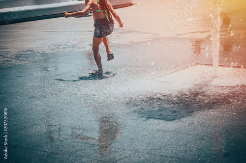 A girl with bare feet playing with a fountain water.