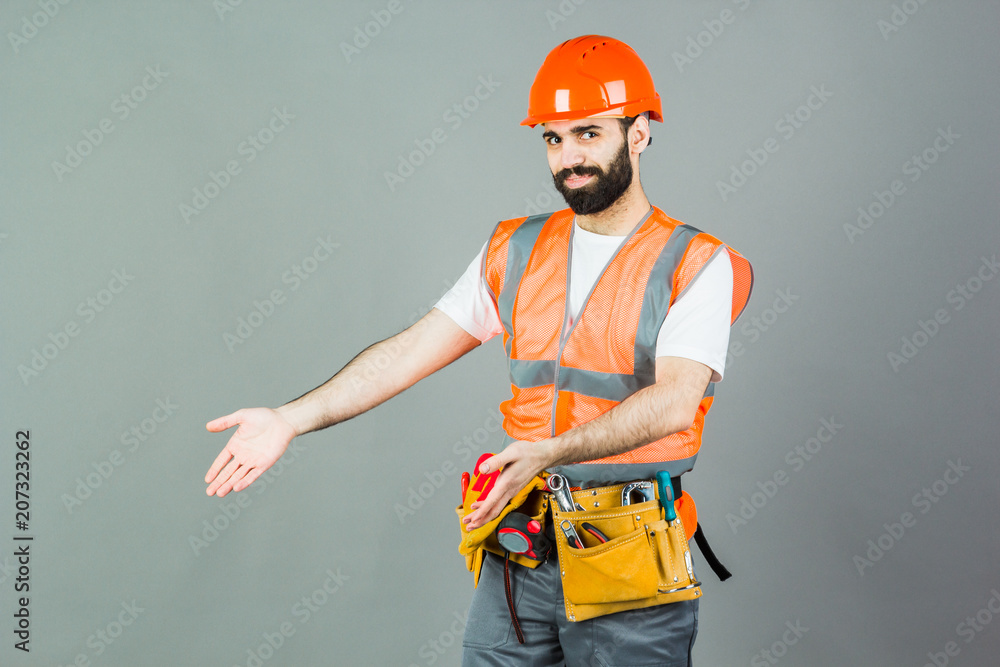 Man Builder with beard standing on gray background, copy space.