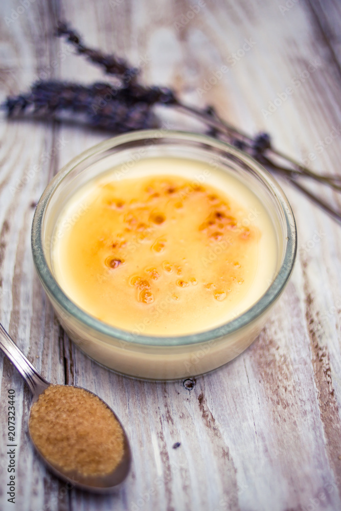 Creme brulee and lavender with cane sugar teaspoon on woody background Creme brulee and lavender with cane sugar teaspoon on woody background