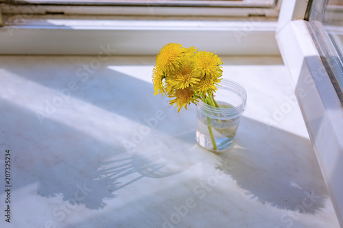 Fototapeta Naklejka Na Ścianę i Meble -  A bouquet of dandelions on the windowsill