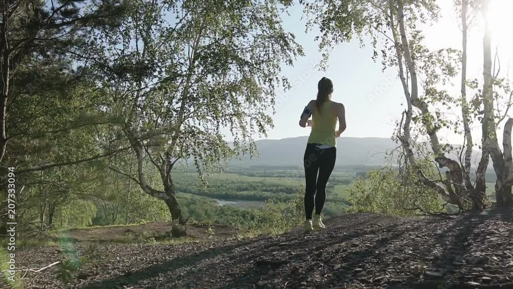 Athlete girl running through forest woods. Real people, woman runner sport training in spring or summer in mountain outdoors nature, sunset Athlete girl running through forest woods. Real people, woman runner sport training in spring or summer in mountain outdoors nature, sunset