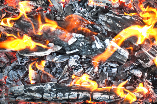 The hot coals with the tongues of flame in the old grill