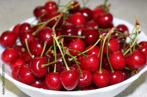 Red ripe cherry lies on a plate