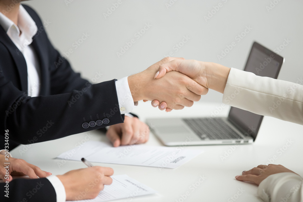 Fototapeta premium Employment handshake concept, female hr and successful woman candidate shaking hands getting hired ready to sign job contract concept, employer congratulating welcoming new worker, close up view