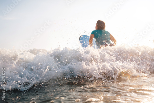 Woman on surfboard swims over the wave