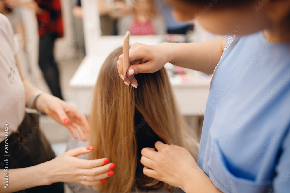 Hairdresser does hairstyle for woman to weave braids, styling. Concept wedding specialist, workshop, training. Hairdresser does hairstyle for woman to weave braids, styling. Concept wedding specialist, workshop, training.