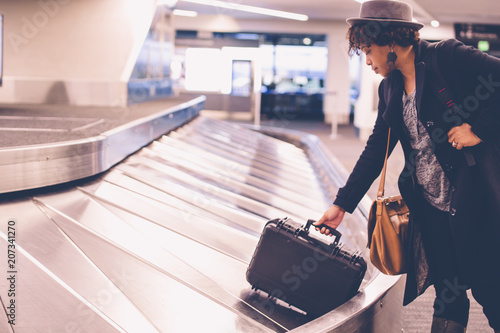 Businesswoman collecting luggage from baggage claim at airport photo