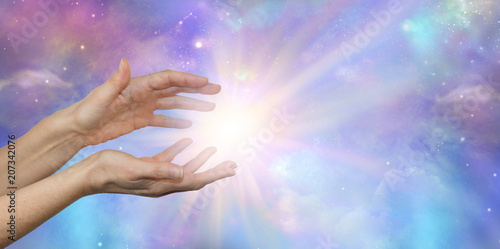 Foto Cosmic Energy - female hands reaching into a bright white cosmic flash against a