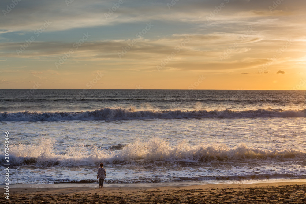 Unidentified woman watching the sunset on Seminyak beach, Bali, Indonesia