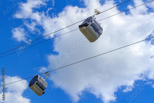 Cabins of a cable car against a blue sky with clouds
