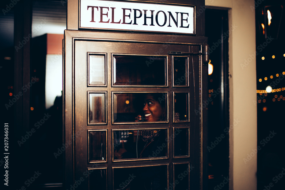 Smiling woman talking on phone in the telephone booth Smiling woman talking on phone in the telephone booth