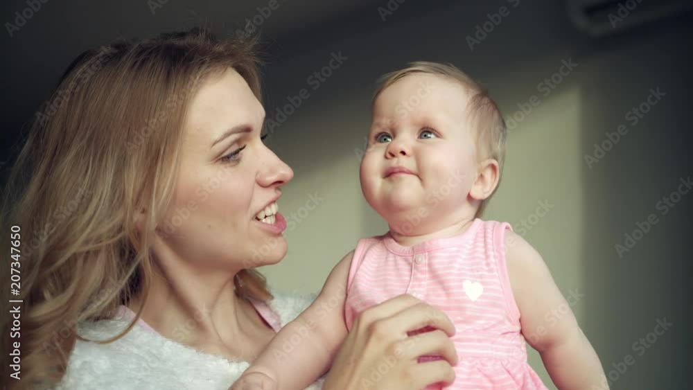 Happy mother holding baby girl on hands. Happy woman with baby on hands. Sweet motherhood. Portrait of mom with daughter at home. Cheerful mom embrace toddler girl. Mom baby love Happy mother holding baby girl on hands. Happy woman with baby on hands. Sweet motherhood. Portrait of mom with daughter at home. Cheerful mom embrace toddler girl. Mom baby love
