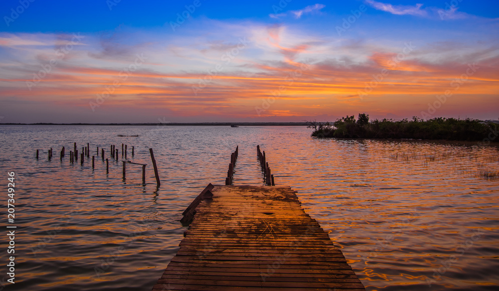 Outdoor view of wooden pier and Bacalar Lagoon suring a gorgeous sunset view in Mayan Mexico at Quintana roo, seven color lake
