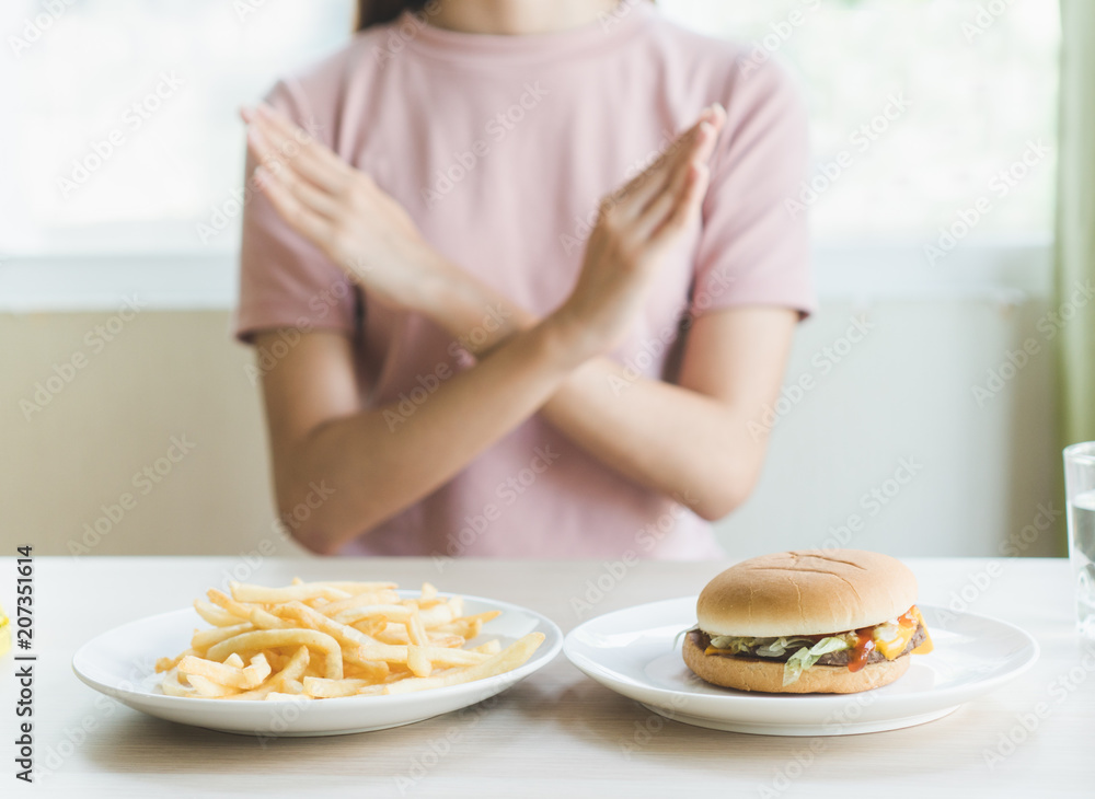 Woman on dieting for good health concept. Woman doing cross arms sign to refuse junk food or fast food (hamburger and potato fried) that have many fat.