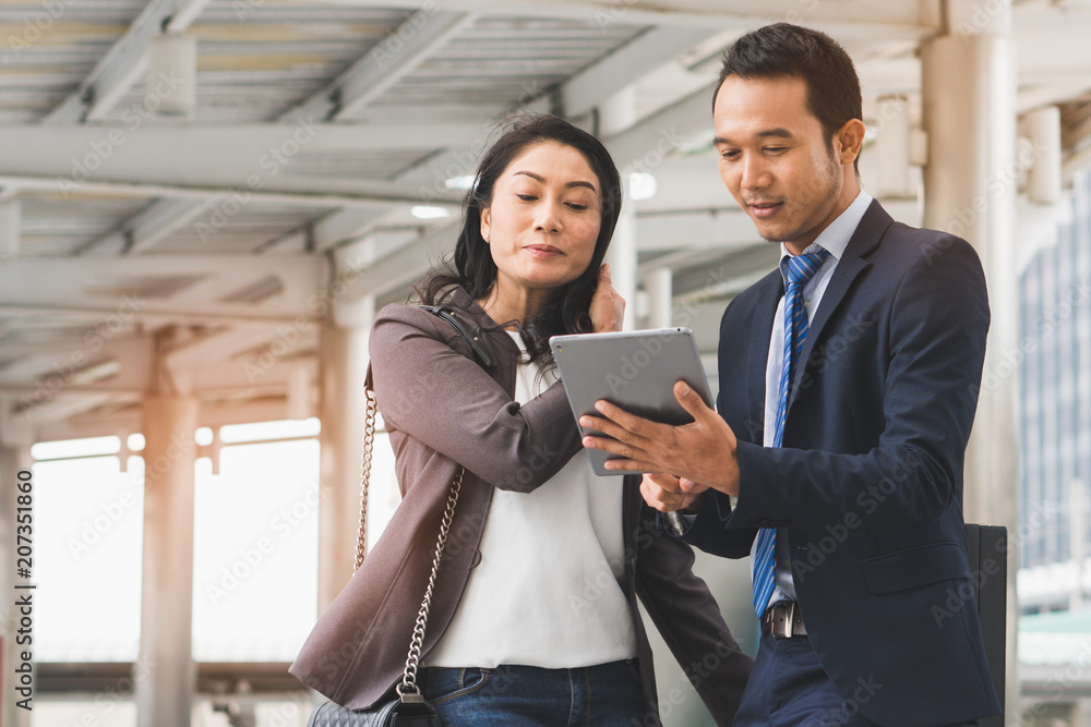 Happy Asian businessmen discussing with female boss in the city. Male open application in tablet showing data to present work. Happy Asian businessmen discussing with female boss in the city. Male open application in tablet showing data to present work.
