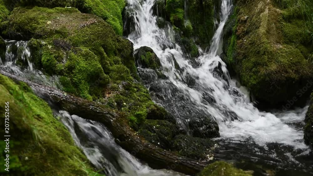 Fast and clear mountain river flowing over rocks covered with moss