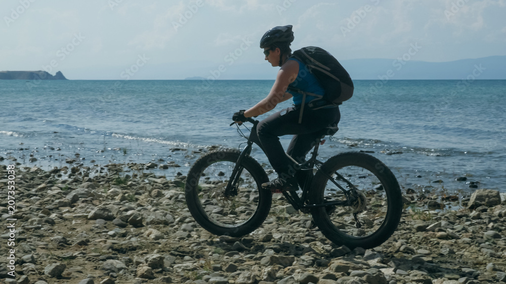Obraz premium Fat bike also called fatbike or fat-tire bike in summer driving on the beach. The guy is going straight on the beach. On the sand on such a bike ride is not difficult.