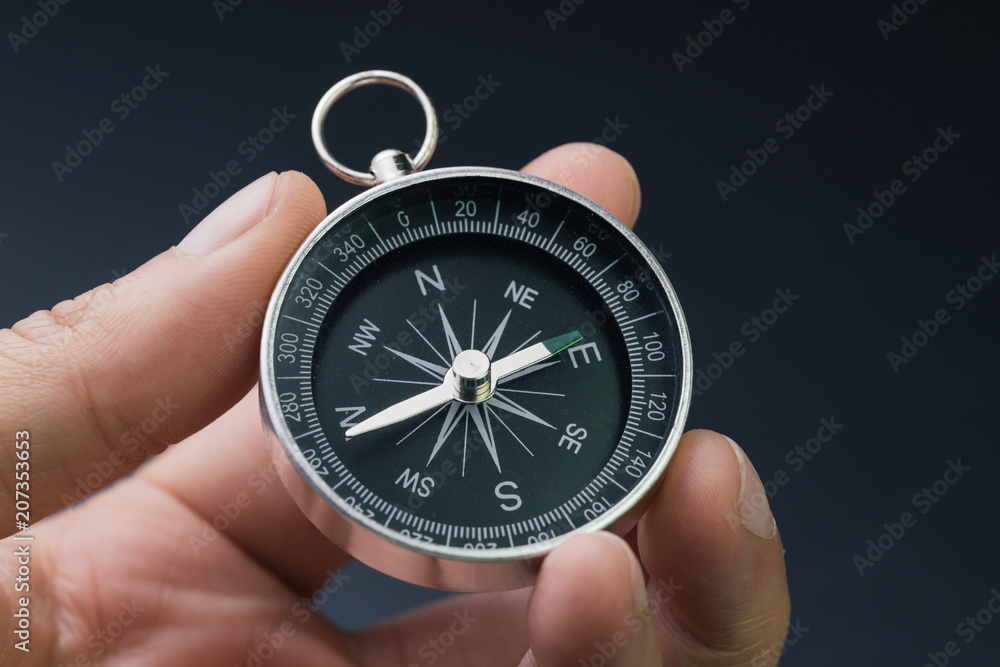 Hand holding compass, business or economy direction, world exploration or decision concept Hand holding compass, business or economy direction, world exploration or decision concept
