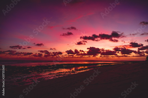 Bright colorful sunset or sunrise at ocean with clouds in tropics
