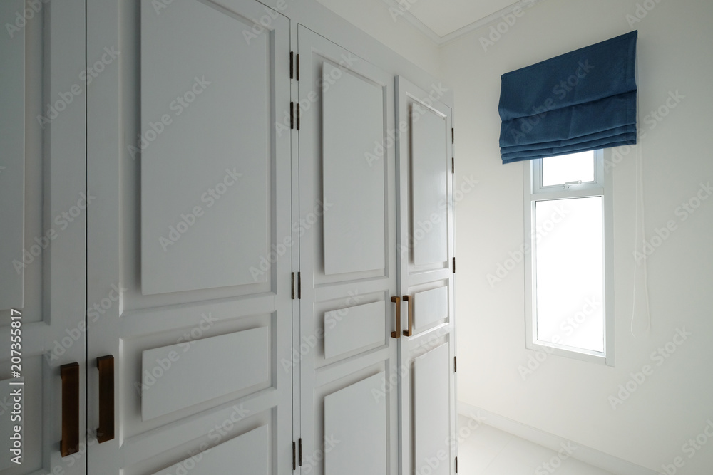 White clothes closet in room with window and navy blue color sun blind keep opened White clothes closet in room with window and navy blue color sun blind keep opened
