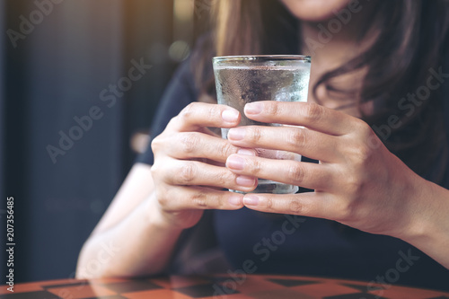 Closeup image of woman holding a glass of cold water to drink