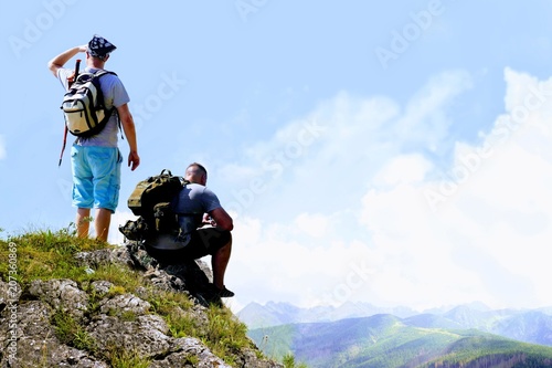 Hikers relaxing on top of a mountain and enjoying the view of valley